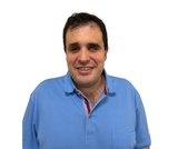 Agustín Aguirre, sonriendo y vestido con un polo azul, fotografiado de frente sobre un fondo blanco